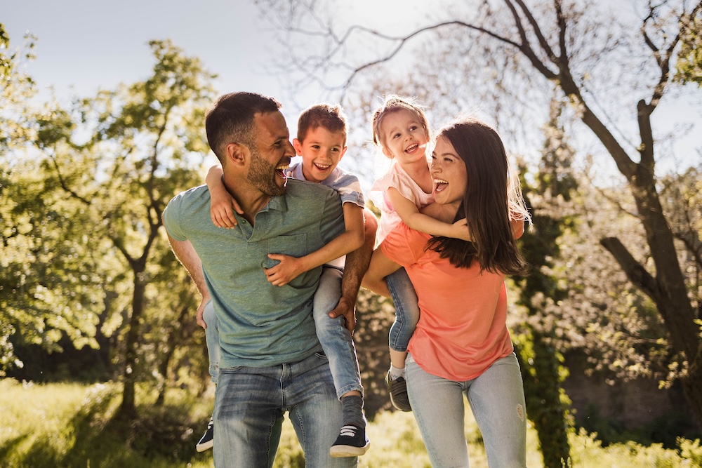 Playful family having fun while piggybacking in springtime.