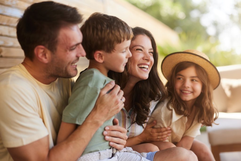 Happy parents enjoying with their small kids during a spring day on a patio. Focus is on woman.